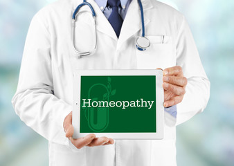 Doctor hands holding tablet with word HOMEOPATHY on screen. Alternative medicine concept.