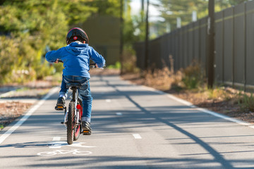 Kid riding his bicycle on bike lane - Powered by Adobe