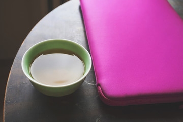 Cup with japanese green tea on the round table with notebook in