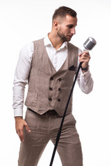 Naklejka premium Young man in suit singing over the microphone with energy. Isolated on white background. Singer concept.