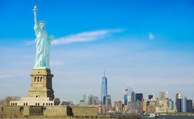 Obraz premium Statue of Liberty on a sunny day, Manhattan in the background. This is a photo-montage, because the statue faces to the viewer