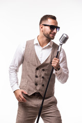 Naklejka premium portrait of young man in suit singing with the microphone. Isolated on grey background. Singer concept.