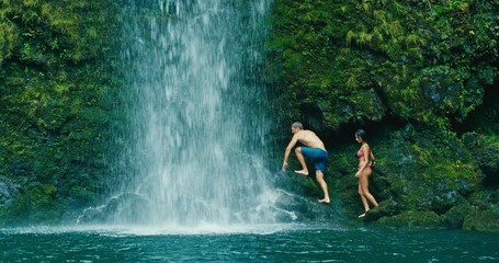 Attractive adventurous young couple exploring beautiful waterfall