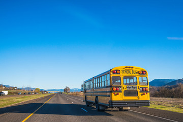 Naklejka na ściany i meble yellow school bus running on the road against the blue sky.