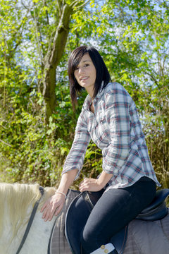 young beautiful brunette woman riding horse