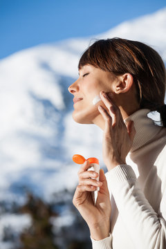 portrait d'une belle femme &agrave; la neige qui s'applique de la cr&egrave;me solaire sur le visage