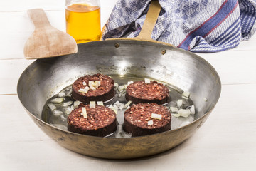 homemade irish black pudding with onion and oil in a brass pan