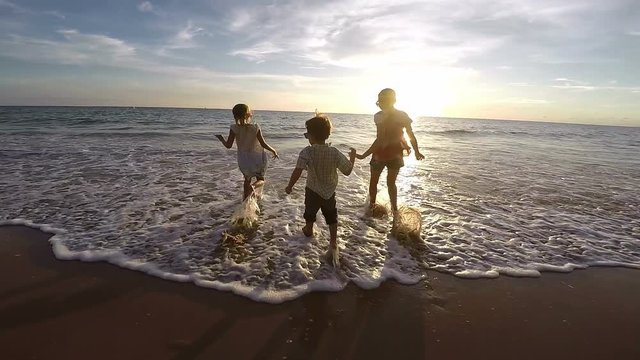 Happy children playing on the beach at the sunset time. Concept of happy friendly family. Video filmed on camera Gopro. 