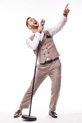 Young showman in suit singing with emotions and pointed  gesture over the microphone with energy. Isolated on white background. Singer concept.