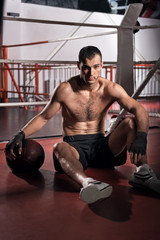 Fototapeta na wymiar Handsome sportsman sitting on floor gym