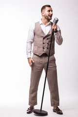 Young showman in suit singing with emotions gesture over the microphone with energy. Isolated on white background. Singer concept.