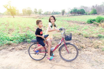 Obraz premium Sister and brother were riding a bicycle in the field.