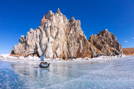 Ice sledge, ski poles and backpack before Shaman Rock at Baikal