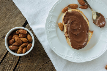 Chocolate paste on piece of bread and almonds top view