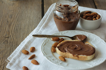 Chocolate paste on piece of bread and almonds copy space
