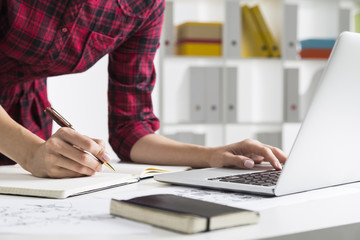 Woman in checkered dress typing and writing