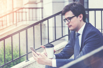 Businessman using phone outside, toned
