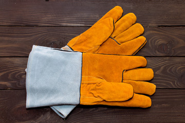 Gloves for welders. Rough leather orange blue gloves for welding works on a wooden background....