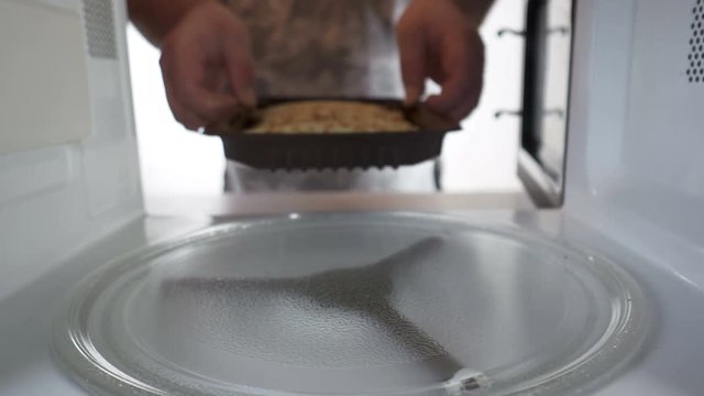 Man cooking breakfast heating pancake rolls in microwave oven