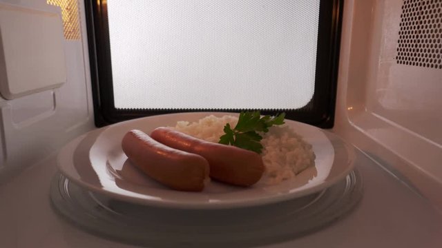 Rice with sausages on a plate heating in the microwave oven inside view. Version without external lighting for more natural look 