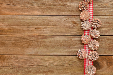 Tannenzapfen und kariertes Band auf Holz