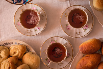 
delicious hot homemade cakes and a cup of tea on a white tablecloth at home at the table