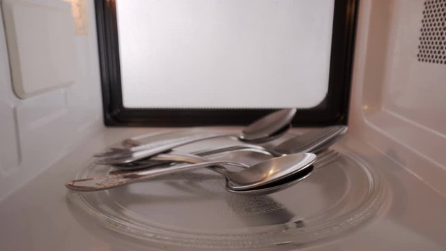 Metal spoons and forks spinning inside microwave oven. Fire and explosion risk