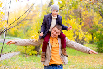 Fototapeta premium Man With Young Son On Shoulders Autumn Park