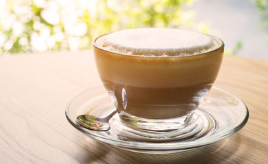 hot cappucino coffee on wood table and green natural background, vintage effect