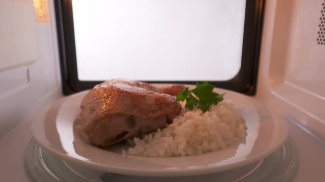 Perfectly cooked pan fried chicken leg with crispy skin and rice garnish heating in the microwave. Version without external lighting for more natural look