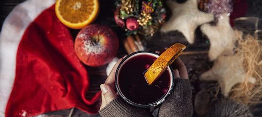 red cup of hot mulled winein hands in winter new year decoration