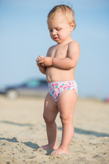 Baby playing with toys on the sandy beach near the sea. Cute little kid in  sand on tropical beach. Ocean coast.