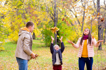 Fototapeta premium family playing with leaves autumn park