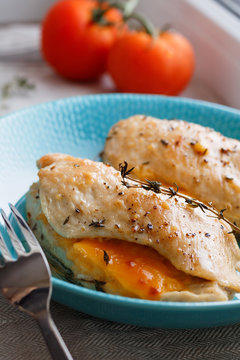 Close-up shot of baked chicken breast with cheese and thyme