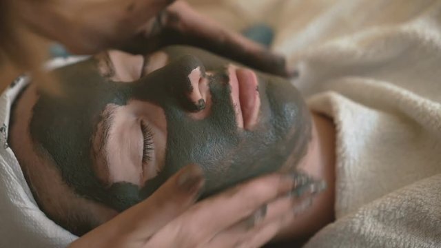 Young woman doing a mud face mask.
