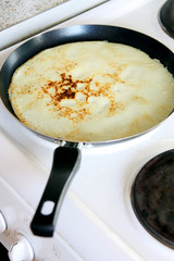 making pancakes: skillet, frying pan with cooked pancake, crepe on white stove