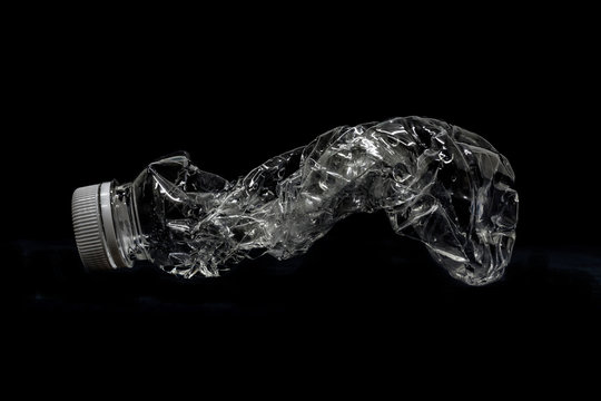 Utilization. Empty, squashed water bottle isolated on black background. recycle concept