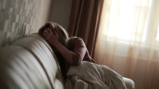 Depressed woman in bed. girl crying on the couch. acute mountain