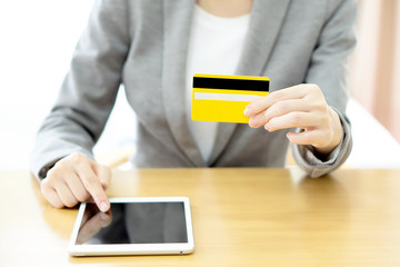Close-up woman's hands holding a credit card and using tablet pc