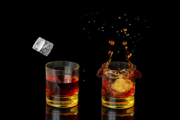 Isolated shot of whiskey with splash on black background.