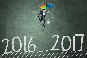 Woman jumps toward 2017 on chalkboard