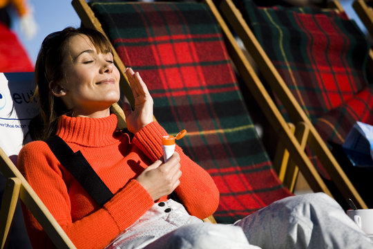 femme souriant en hiver qui applique une cr&egrave;me de protection 