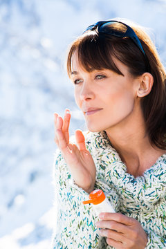portrait d'une belle femme qui met de la cr&egrave;me en hiver