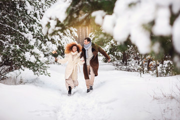 Winter love. Happy couple, bride and groom in warm clothes running in snowy winter forest at their wedding day. Warm and snowy winter wedding day