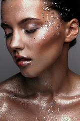Girl with creative makeup with sequins in studio