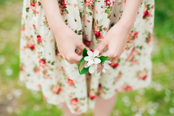 Obraz na płótnie Canvas girl in flower dress holding sakura cherry blossom in hands