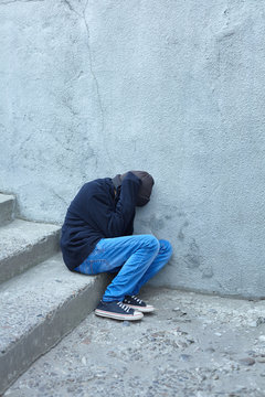 young homeless boy sleeping on the street