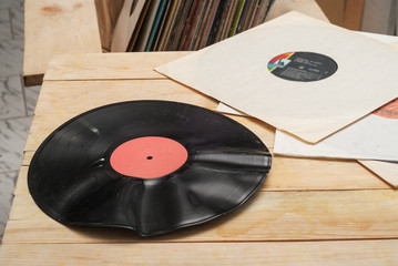 Retro styled image of a collection of old vinyl record lp's with sleeves on a wooden background. Browsing through vinyl records collection. Music background. Copy space