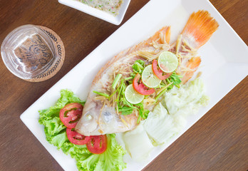 Steamed fish with chili and lemon on wood table , spicy food