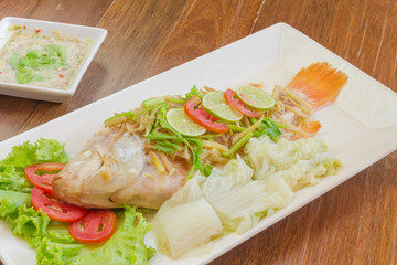 Steamed fish with chili and lemon on wood table , spicy food